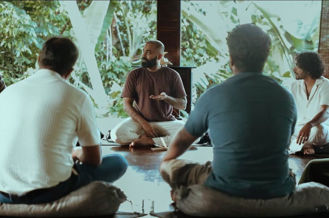 Founders seated on cushions in a circle in an open-air yoga shala